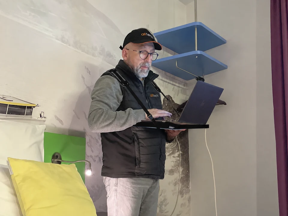 Olivier, casquette Alltech sur la tête, effectue une mesure Wi-Fi sur son ordinateur dans une chambre.