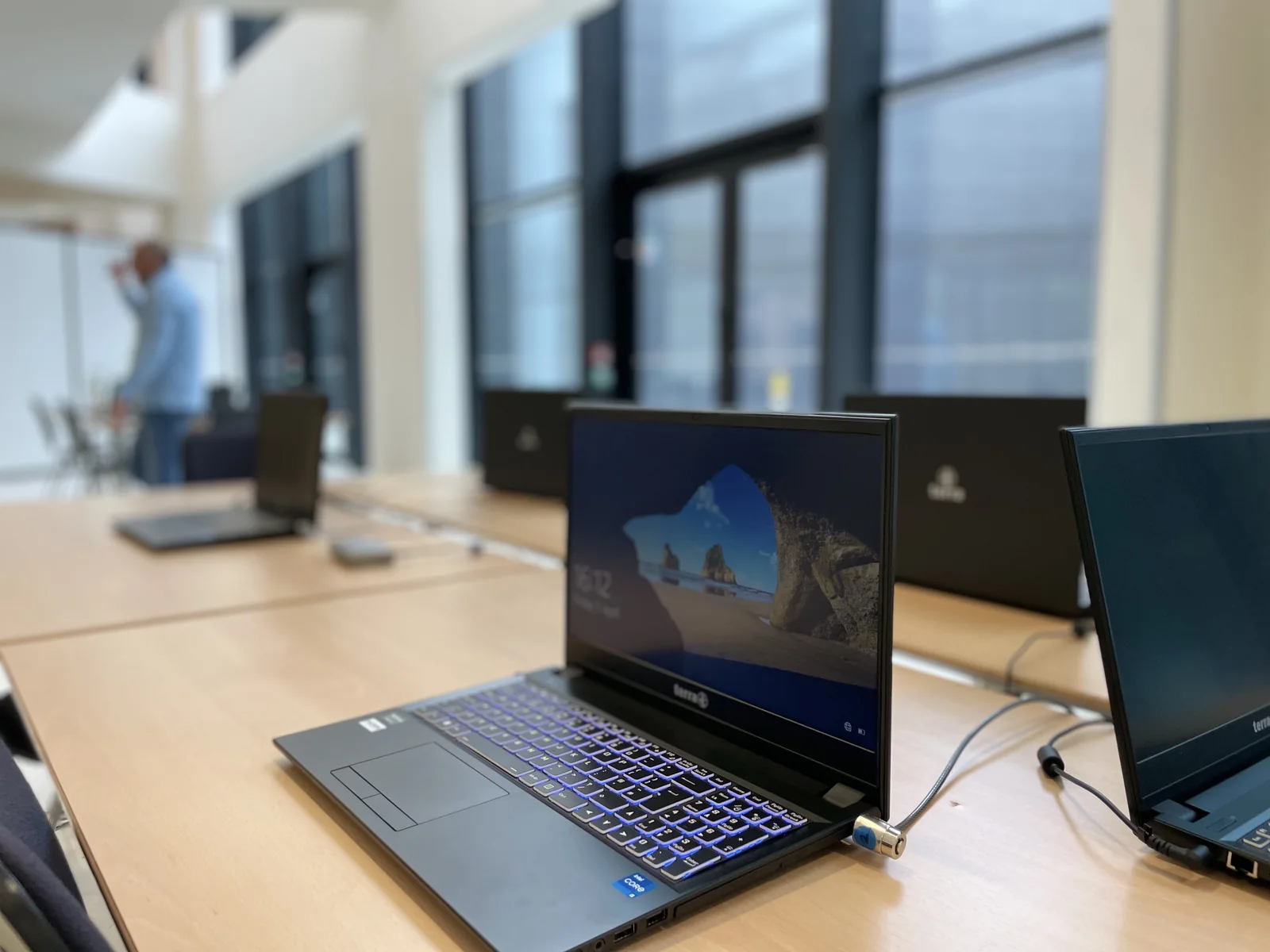 Plusieurs ordinateurs préparés sur des tables de travail.