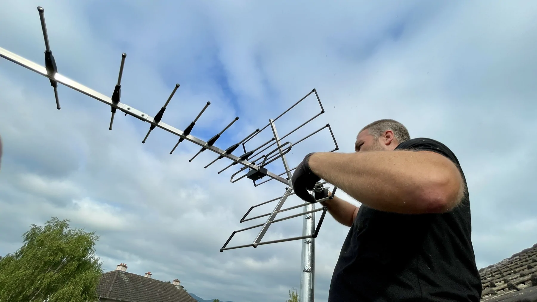 Technicien Alltech manipulant la fixation d’une antenne terrestre sur son mât.