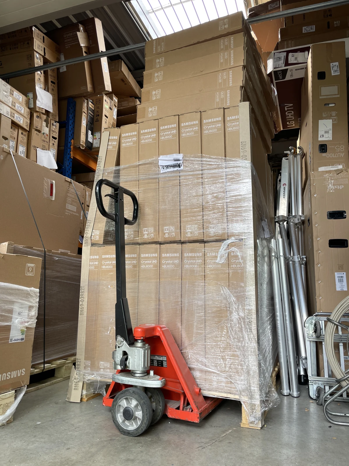 Palettes de téléviseurs dans le stock avec un transpalette.