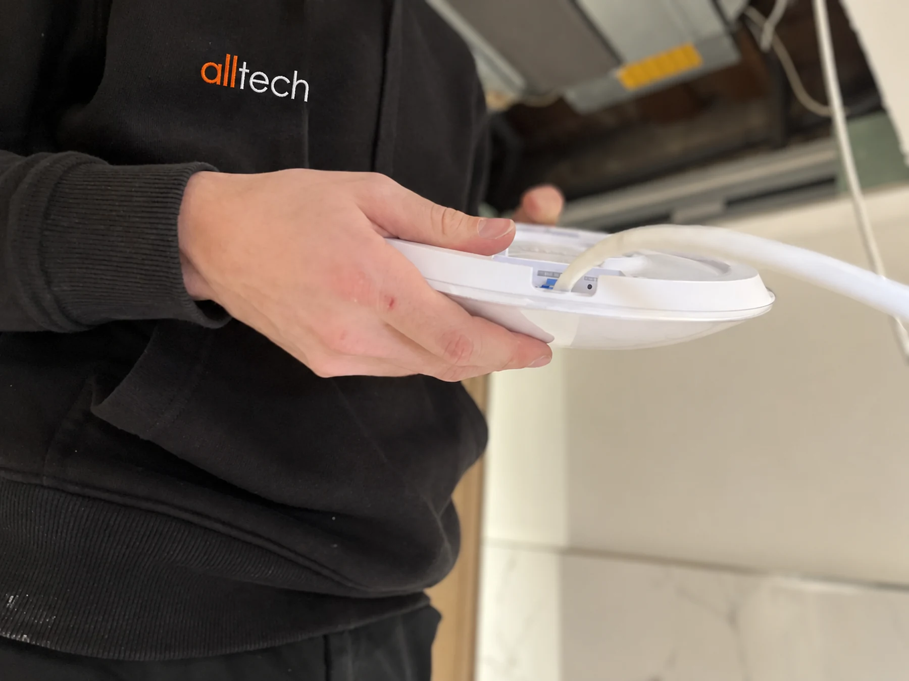 Mains tenant un point d’accès Wi-Fi avec son câble réseau raccordé.