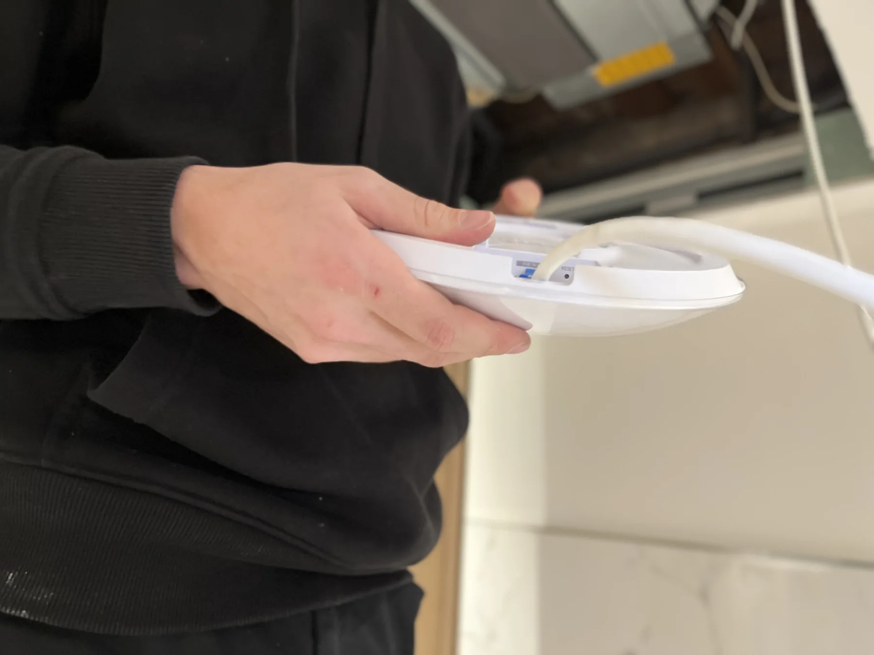 Mains tenant un point d’accès Wi-Fi avec son câble réseau raccordé.