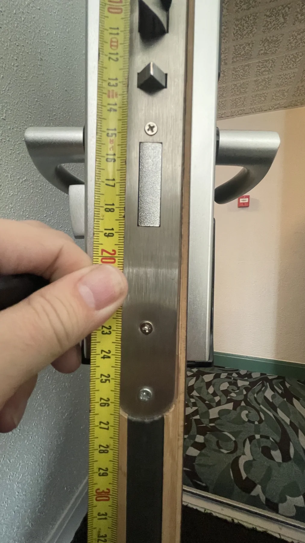 Mesure de la têtière d’une serrure sur la tranche d’une porte.