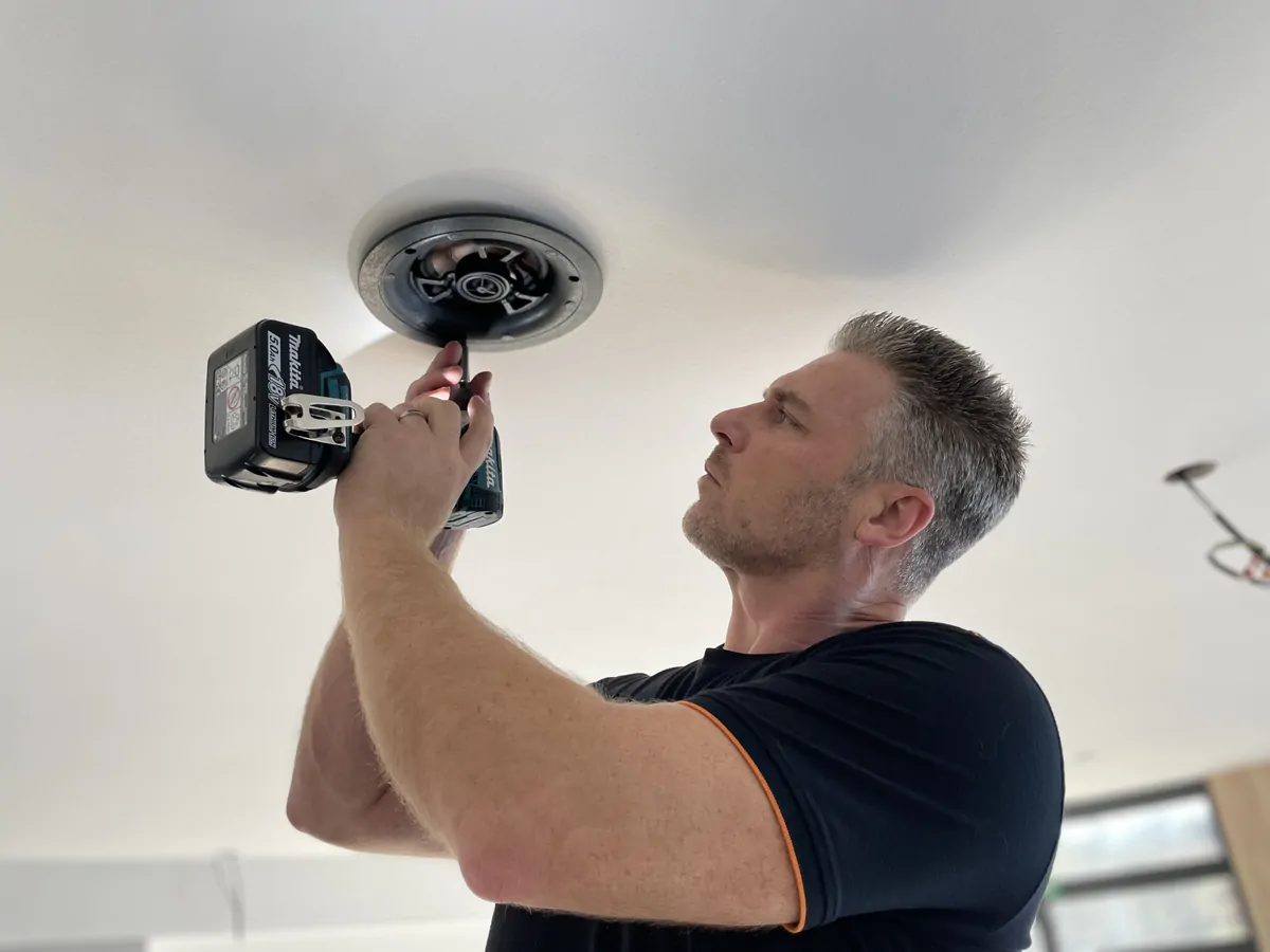 Technicien Alltech installant un haut-parleur encastré au plafond